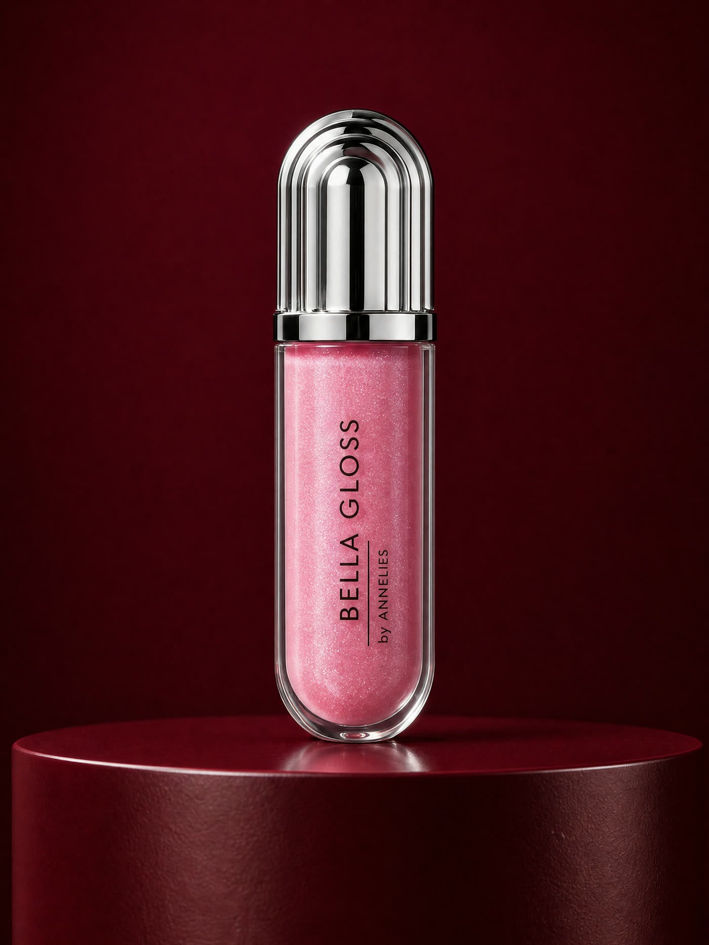 De tube Bella Gloss in rozeroze shimmer op een diepbordeaux sokkel