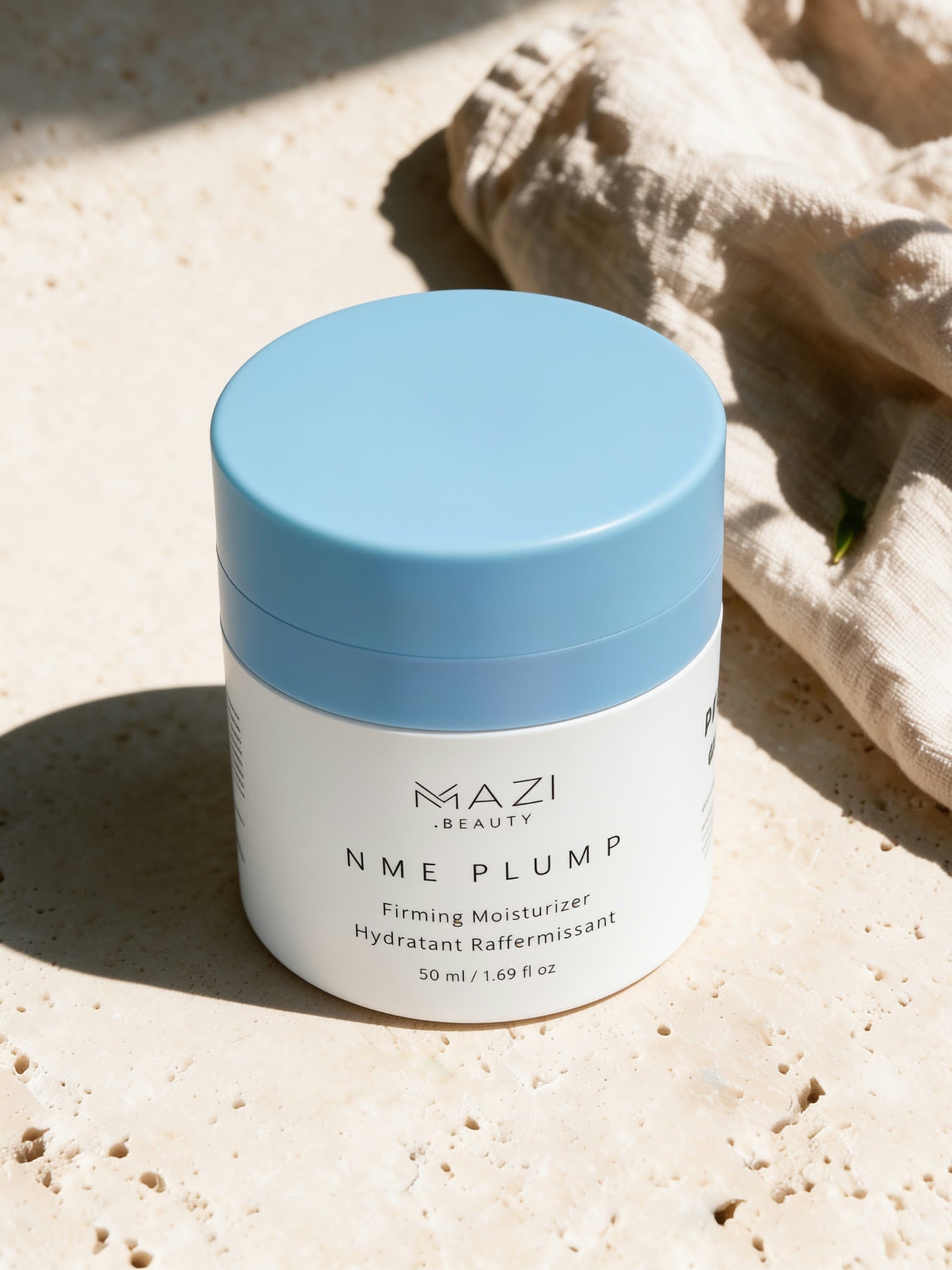 The closed NME Plump jar on sunlit travertine beside linen
