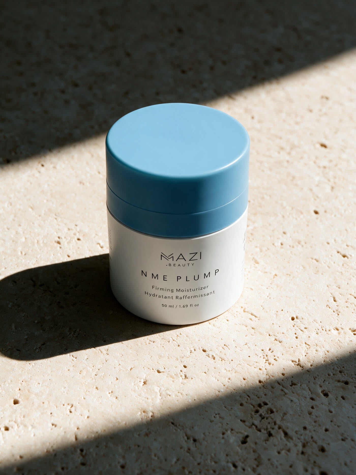 Le pot fermé de crème NME Plump à la limite entre soleil et ombre portée